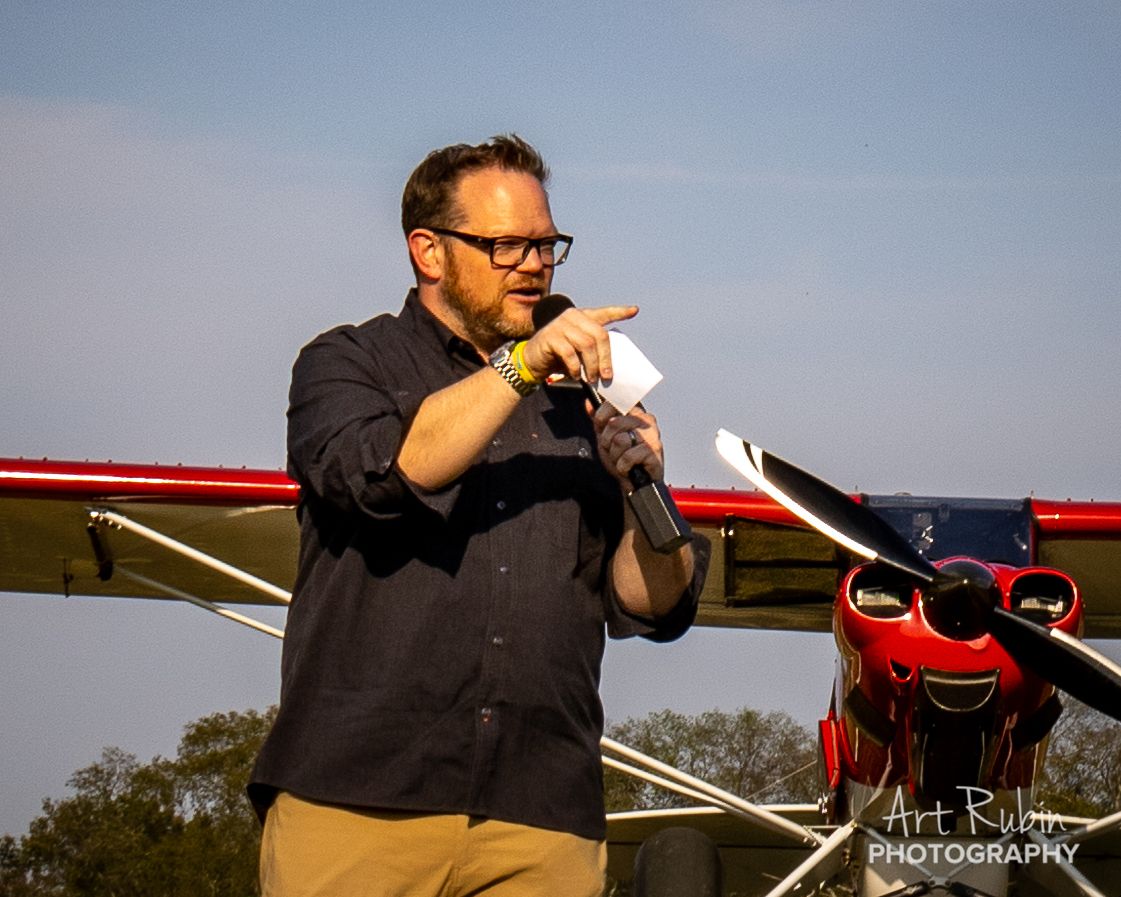 Emcee on the mic beside a competitor aircraft