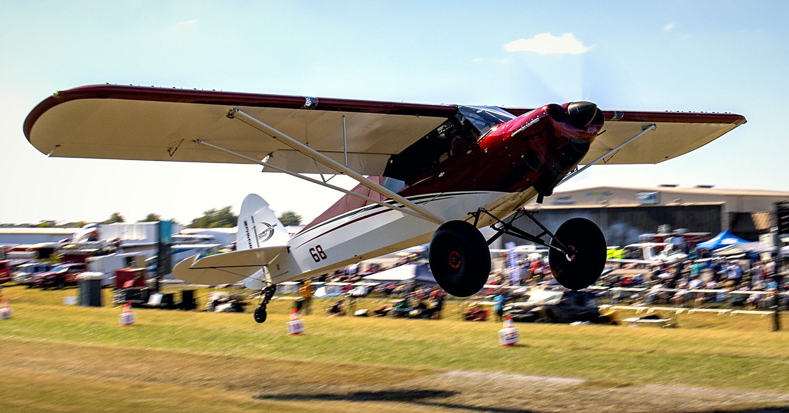 Bush plane landing with the crowd and tents behind