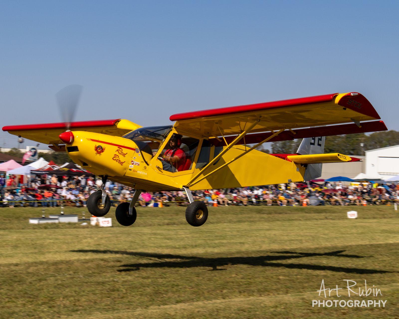 Red Bird airborne against a massive crowd backdrop