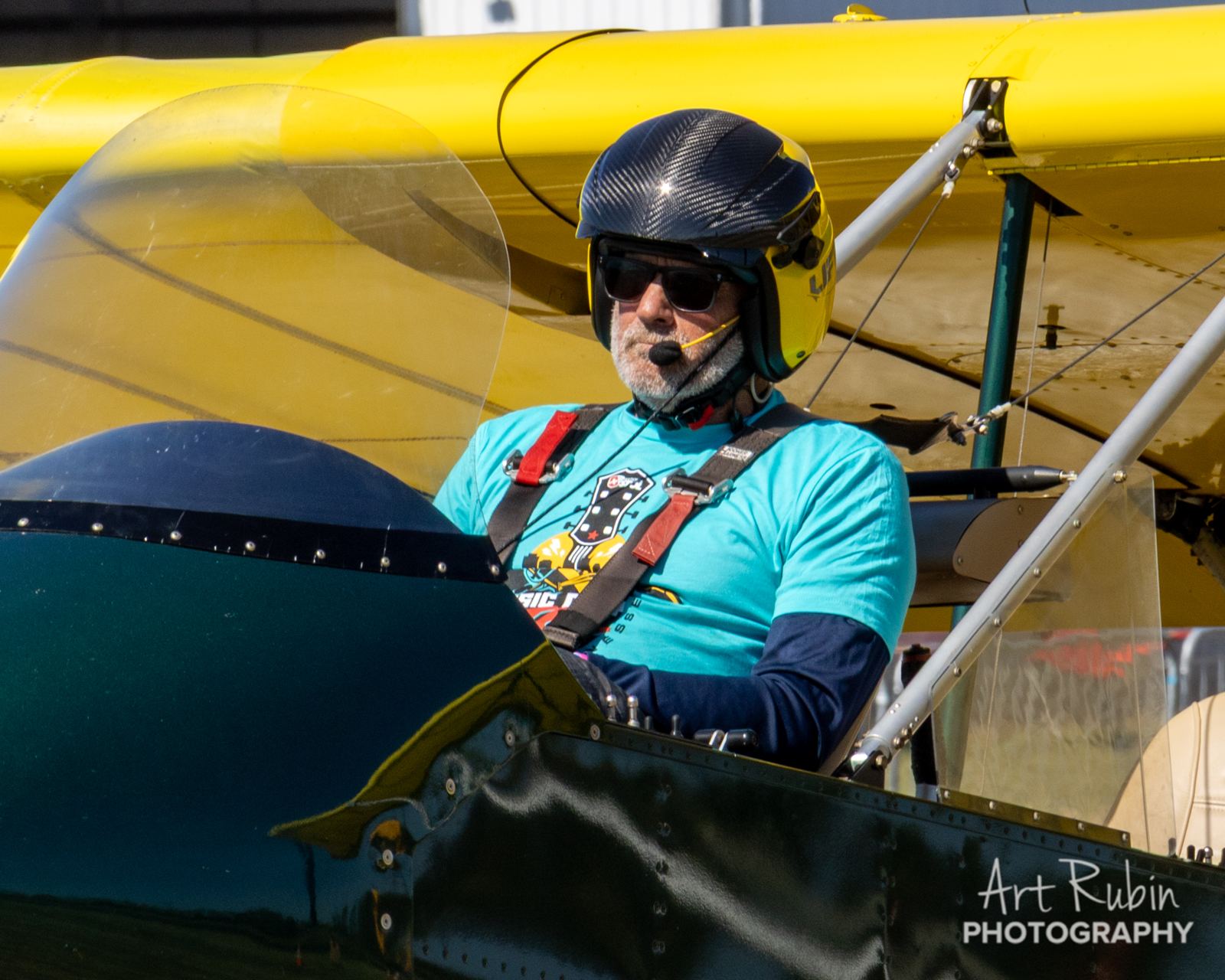 Pilot strapped in and ready under a yellow wing