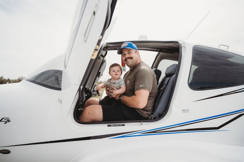 A dad and his baby try out the cockpit of a display aircraft