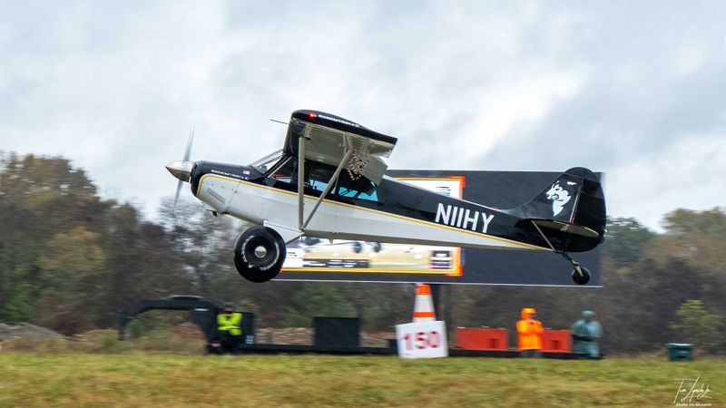 Race 16 · Brad Crawford · Aviat Husky N11HY over the 150-foot marker in the rain